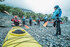Grupo de personas recibiendo instrucciones para remar en kayak en la costa de Lago Grey, rodeados de árboles nativos en Torres del Paine.