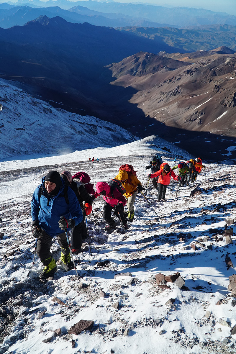 Mountaineers in the final stage of the ascent to Cerro El Plomo, walking on snow in the Andes Mountains, Chile