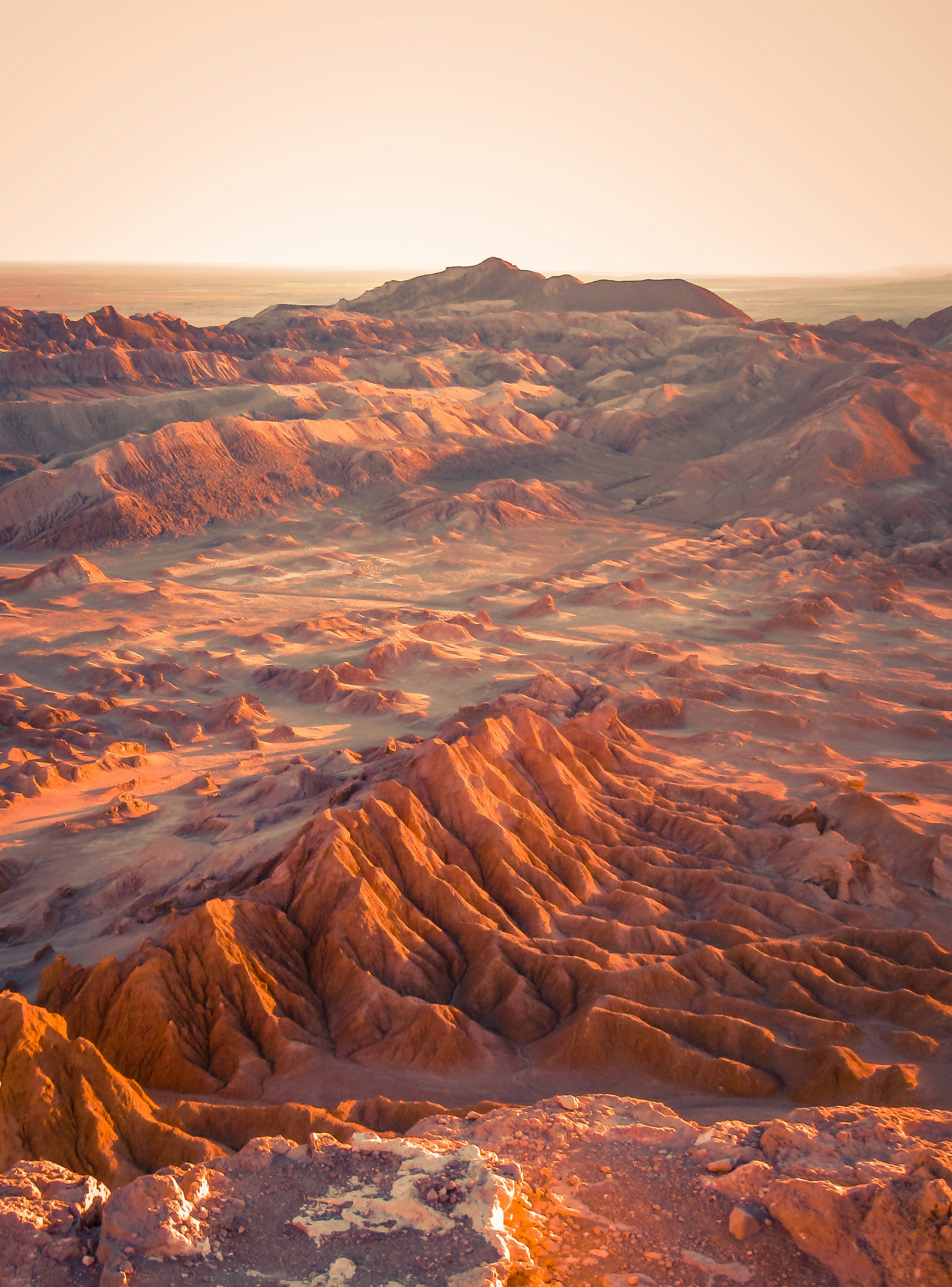 Panoramic view of the Valley of the Moon in San Pedro de Atacama, Chile, at sunset, with rock formations and warm desert colors.