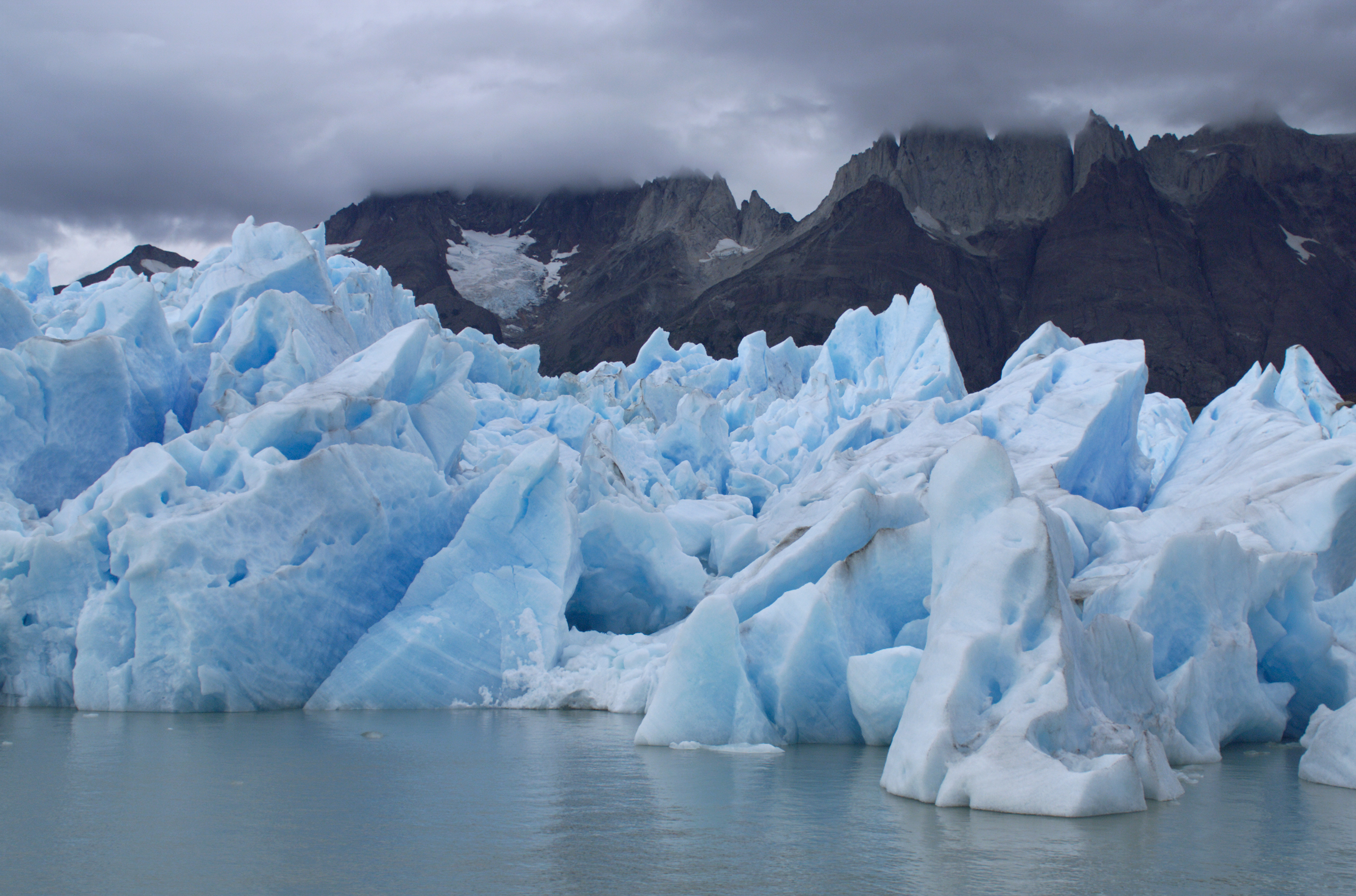Blue icebergs of the Grey Glacier floating in Lake Grey with the Cuernos del Paine covered in clouds in the background, in Torres del Paine.