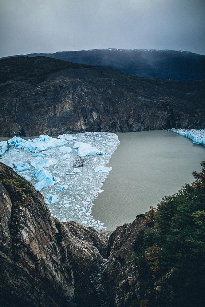 View from the upper viewpoint of the Grey Glacier in Torres del Paine, with icebergs floating on Lake Grey and rocky walls framing the landscape.