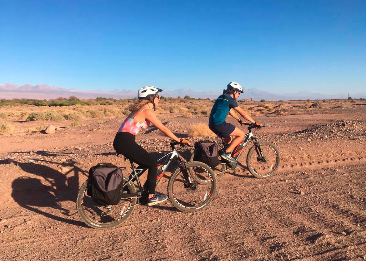 Couple riding through the Atacama Desert on an electric bike during an excursion in San Pedro de Atacama.