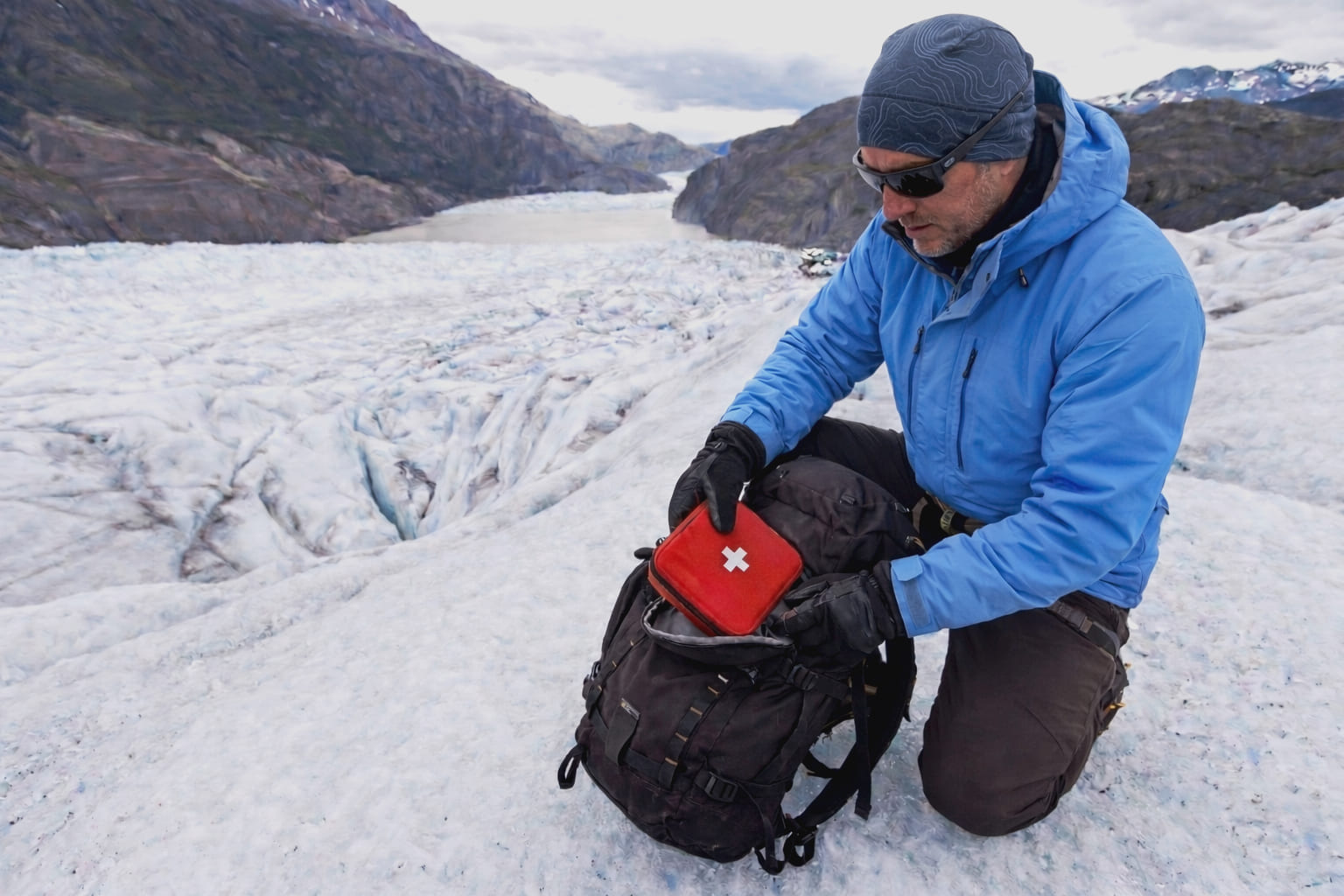 徒步旅行者在冰川山区徒步旅行时从背包中拿出急救包。